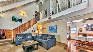 A spacious living area with a large couch, a coffee table, and a staircase leading to an upper level.