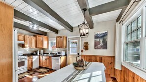 A modern kitchen with wooden cabinets, a central island, and a dining area with a table set for two.