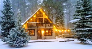 A cabin with a balcony, surrounded by snow-covered trees. - Caring Bear Cabin - games, pets, wheelchair-friendly (South Lake Tahoe)