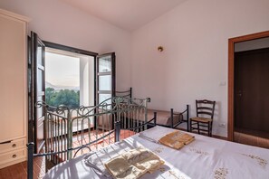 Une chambre avec un lit, une chaise, une armoire et un balcon offrant une vue.