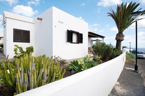 Un edificio blanco con un letrero 'PARK LOB', una palmera y cactus.
