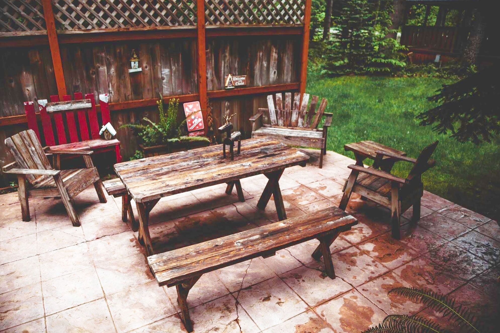 Une terrasse extérieure aménagée avec des meubles en bois rustique, notamment une table et des chaises, posés sur un sol carrelé.
