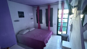 Een slaapkamer met een bed, een raam met gordijnen, een wandairconditioner en een kleine tafel.