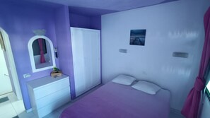Ein Schlafzimmer mit einem Bett, einem Schminktisch, einem Spiegel und einer Tür.