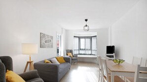 Ein modernes Wohnzimmer mit einem grauen Sofa, einem Holzesstisch und einem Fernseher.