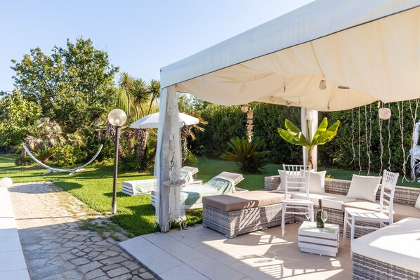 Une terrasse avec mobilier d’extérieur, une pergola et un jardin.