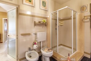 A bathroom with a toilet, bidet, and a glass-enclosed shower.