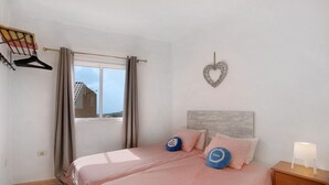 Une chambre à coucher avec un lit, une table de chevet, un décor mural en forme de cœur et une fenêtre avec des rideaux.