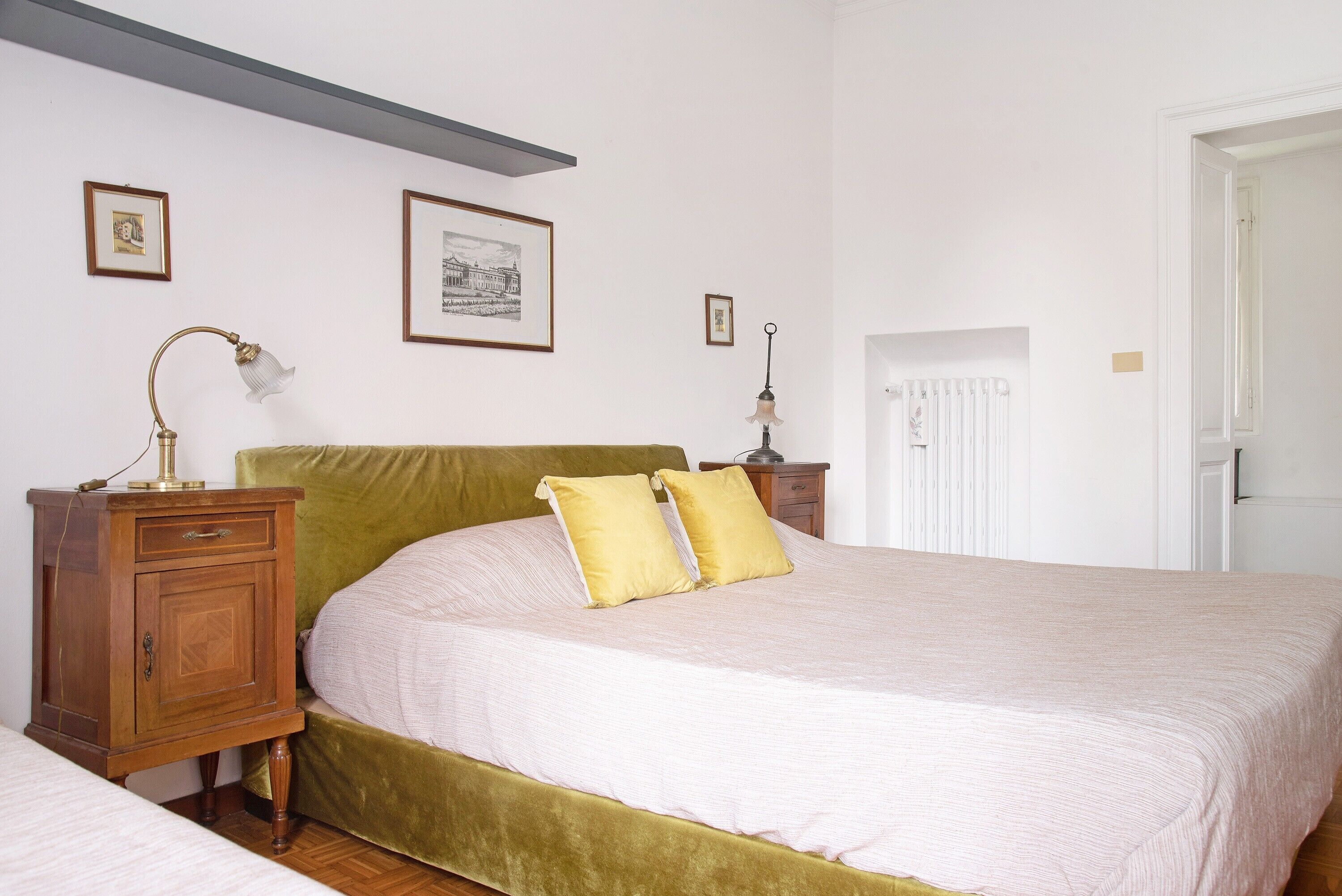 A bedroom with a bed, a nightstand, a lamp, and framed pictures on the wall.