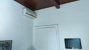 Una habitació amb sostre de fusta, una porta blanca i un televisor penjat.