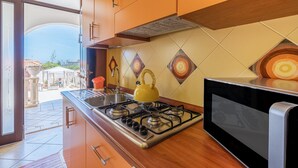 Une cuisine équipée d’une cuisinière à gaz, d’un four à micro-ondes et d’une bouilloire jaune.