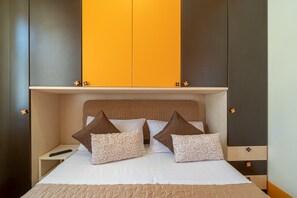Un lit avec une tête de lit, des oreillers, une télécommande et une table de chevet.
