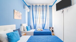 A bedroom with two beds, a TV, and a window with curtains.