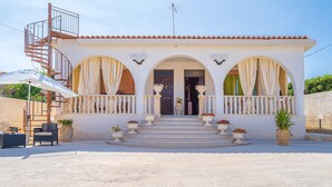 A white building with a spiral staircase, arched windows, and a balcony.