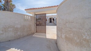 A gated entrance to a building with a tiled roof and a staircase leading to an upper level.
