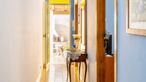 A hallway with a wooden door, a table with a vase, and a chair.