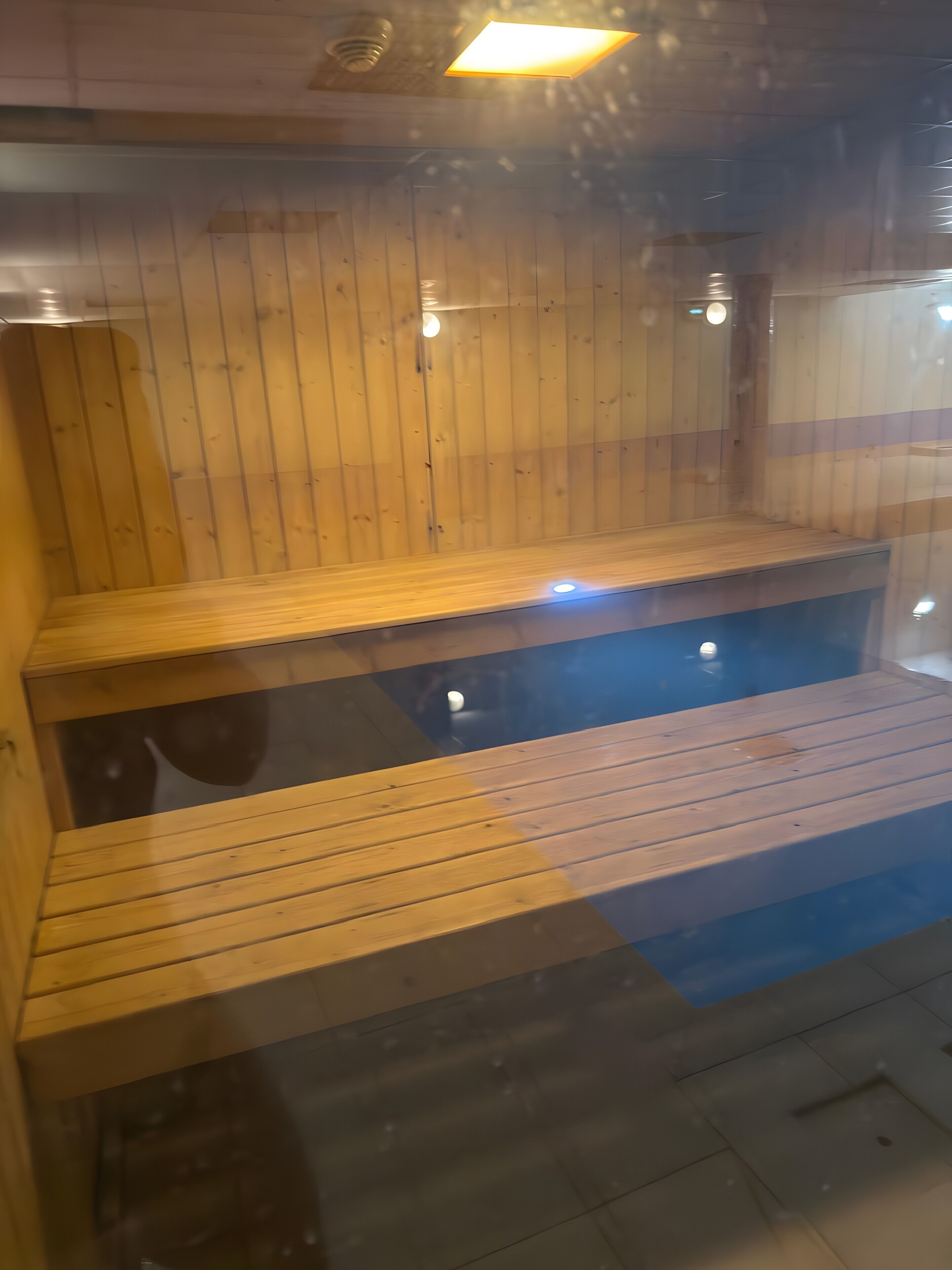 A wooden sauna with benches and a glass enclosure.