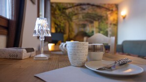 A wooden table with a cup, saucer, and utensils, a candle, and a lamp. - '12 MN Megève Studio Comfort' with Mountain View (Flumet)