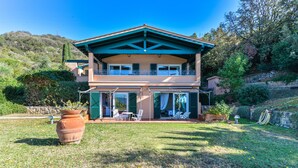 Une maison à deux étages avec un balcon, une pelouse et un grand pot en terre cuite.