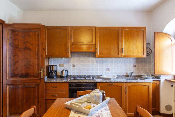 A kitchen with wooden cabinets, a stove, a sink, and a dining table with chairs.