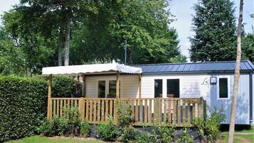A mobile home with a wooden deck, a covered porch, and a small garden area.