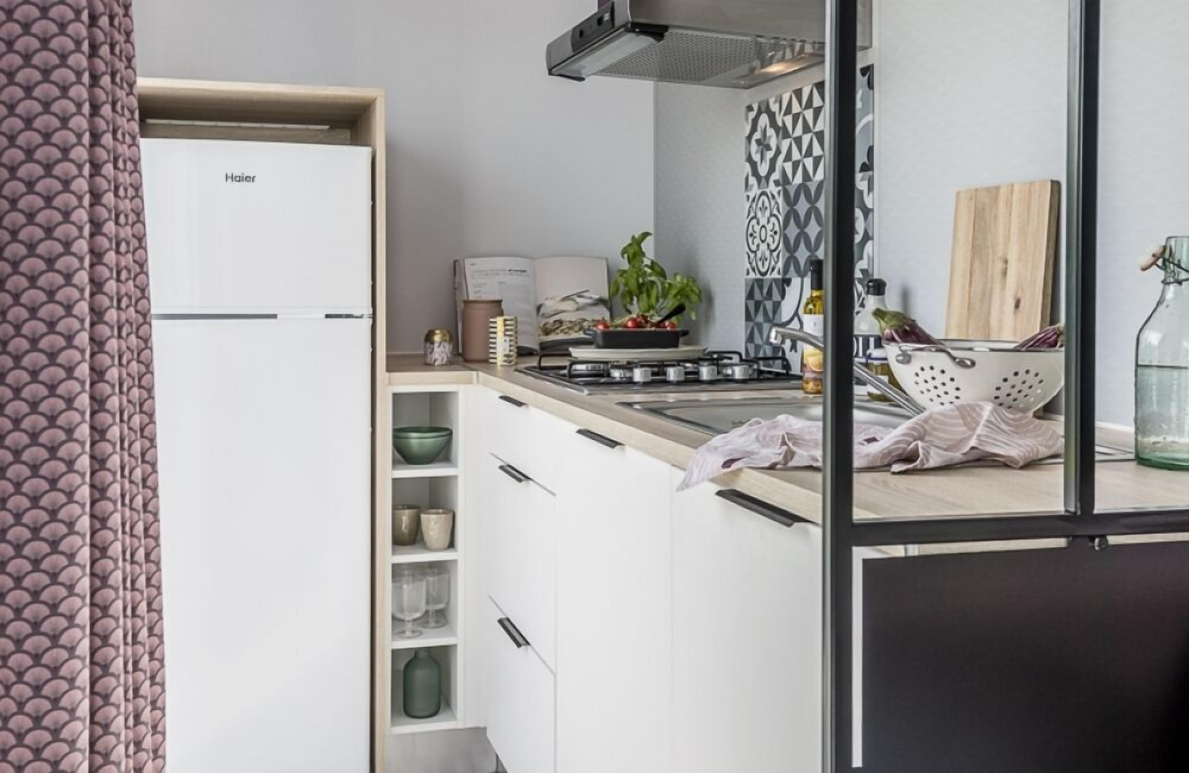 Una cocina compacta con armarios blancos, una estufa a gas y una pequeña encimera.