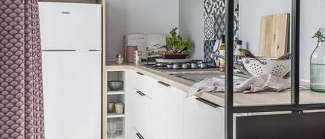 Una cocina compacta con armarios blancos, una estufa a gas y una pequeña encimera.