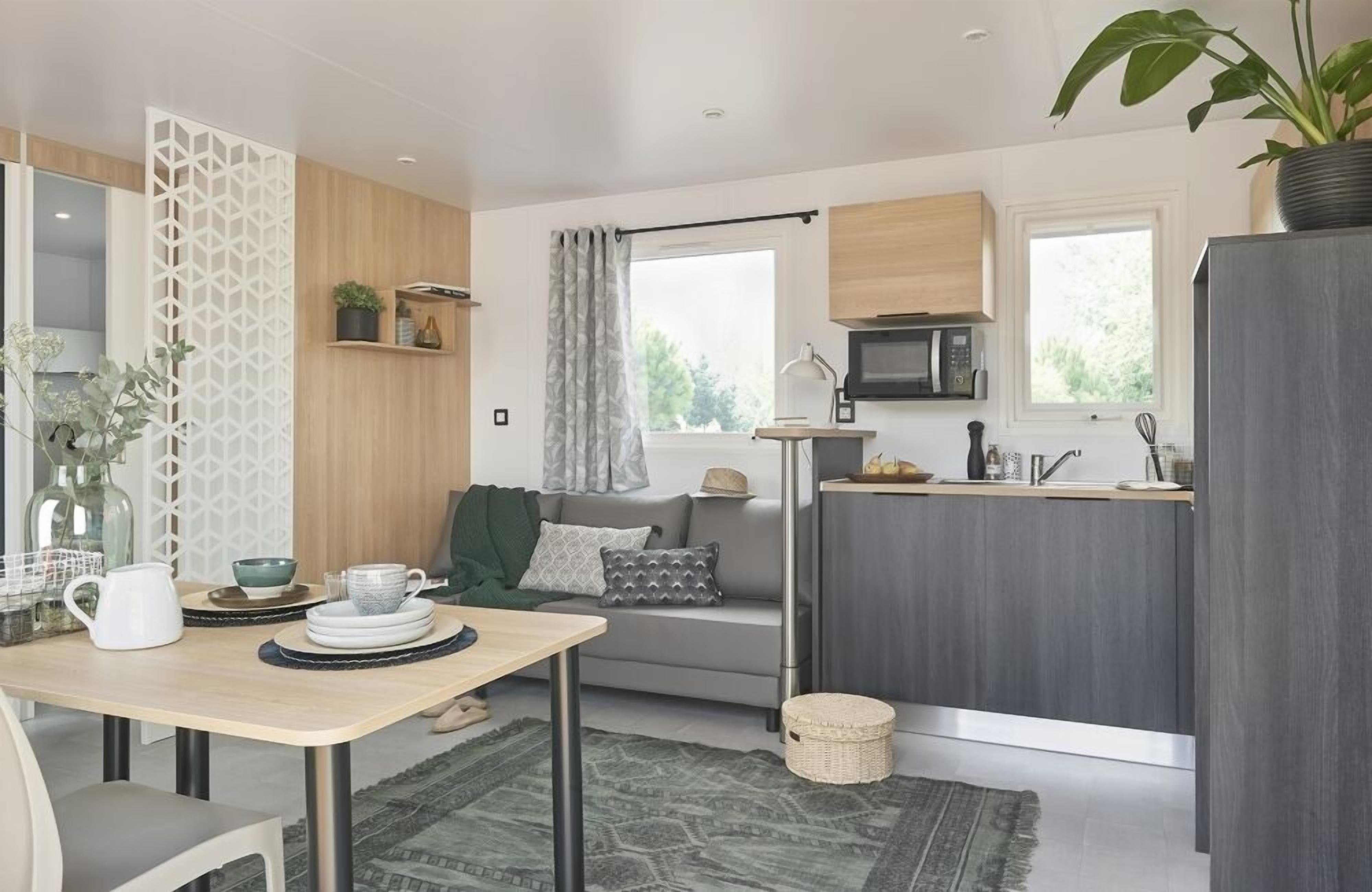 A compact kitchen with a microwave, sink, and a small dining area with a table and chairs.