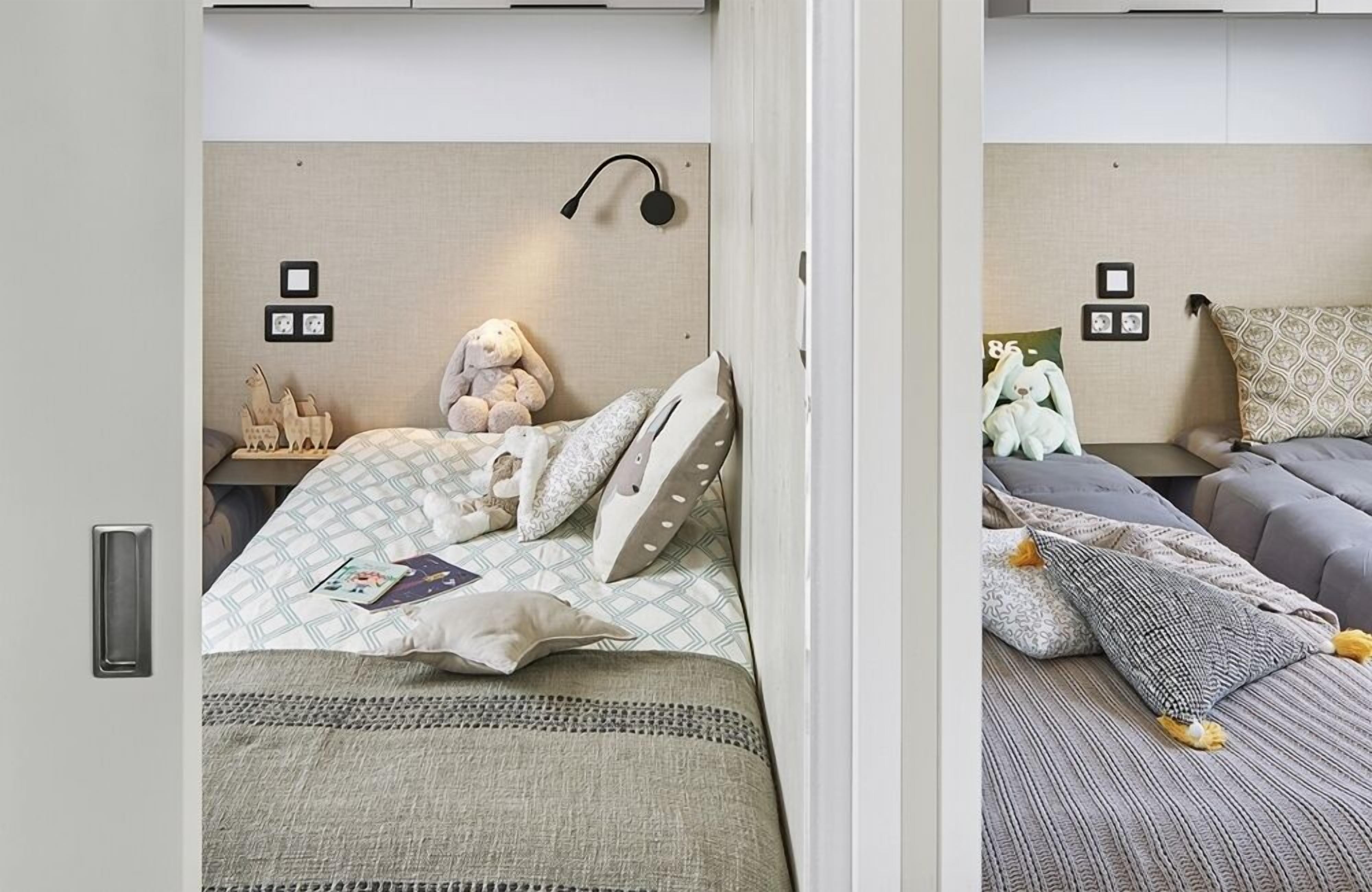 A bedroom with a bed, bedside table, and wall-mounted lamp.