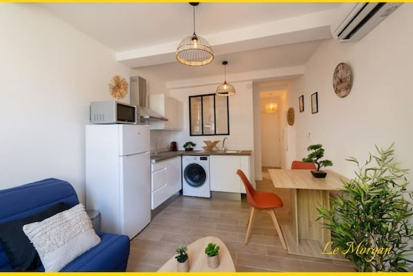 A compact living space with a kitchenette, a dining area, and a seating area with a sofa and a small table.