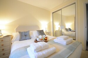 Ein Hotelzimmer mit einem großen Bett, Nachttischen, einem Spiegel und einem Kleiderschrank.