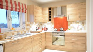 Eine moderne Küche mit Holzschränken, einer Edelstahl-Spüle und einem roten Gerät.