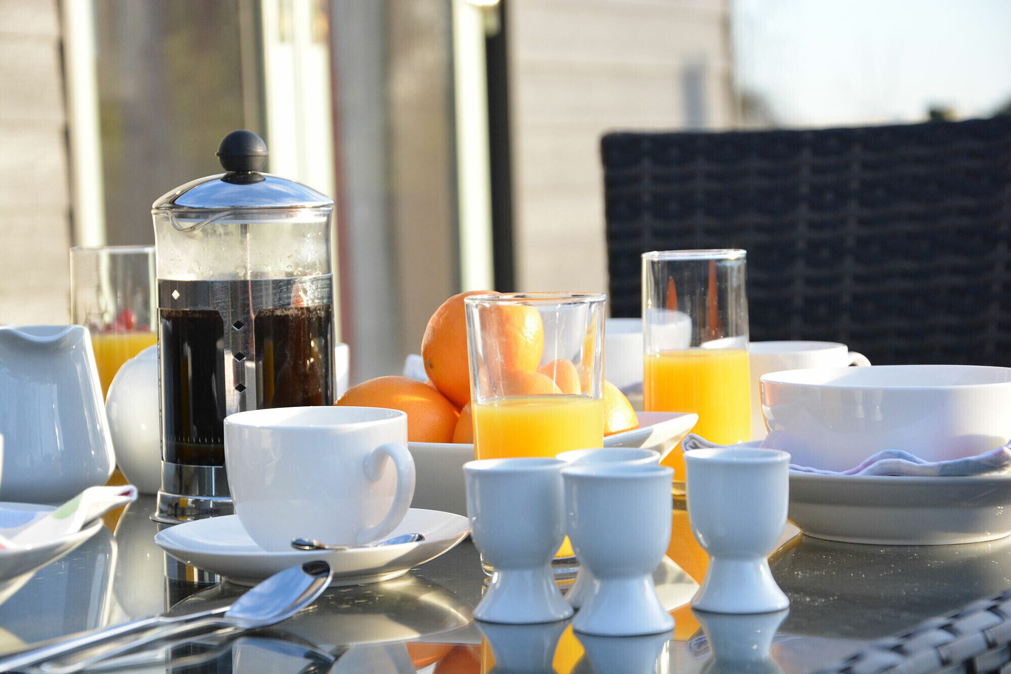 Una mesa de desayuno con café, jugo de naranja y frutas cítricas.