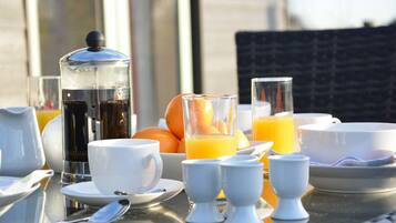 Una mesa de desayuno con café, jugo de naranja y frutas cítricas.
