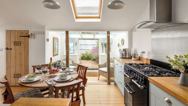 A modern kitchen with a skylight, wooden dining table, and a view of the garden. - 7 Church Street, Southwold (Reydon)