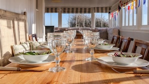 A dining area with a wooden table set for a meal, surrounded by chairs. - Valetta, Thorpeness (Leiston)