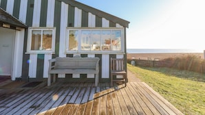 A wooden deck with a bench and a chair, overlooking a beach. - Valetta, Thorpeness (Leiston)