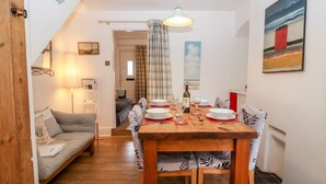 A cozy dining area with a wooden table set for four, a sofa, and a lamp. - Holmleigh, Aldeburgh (Aldeburgh)
