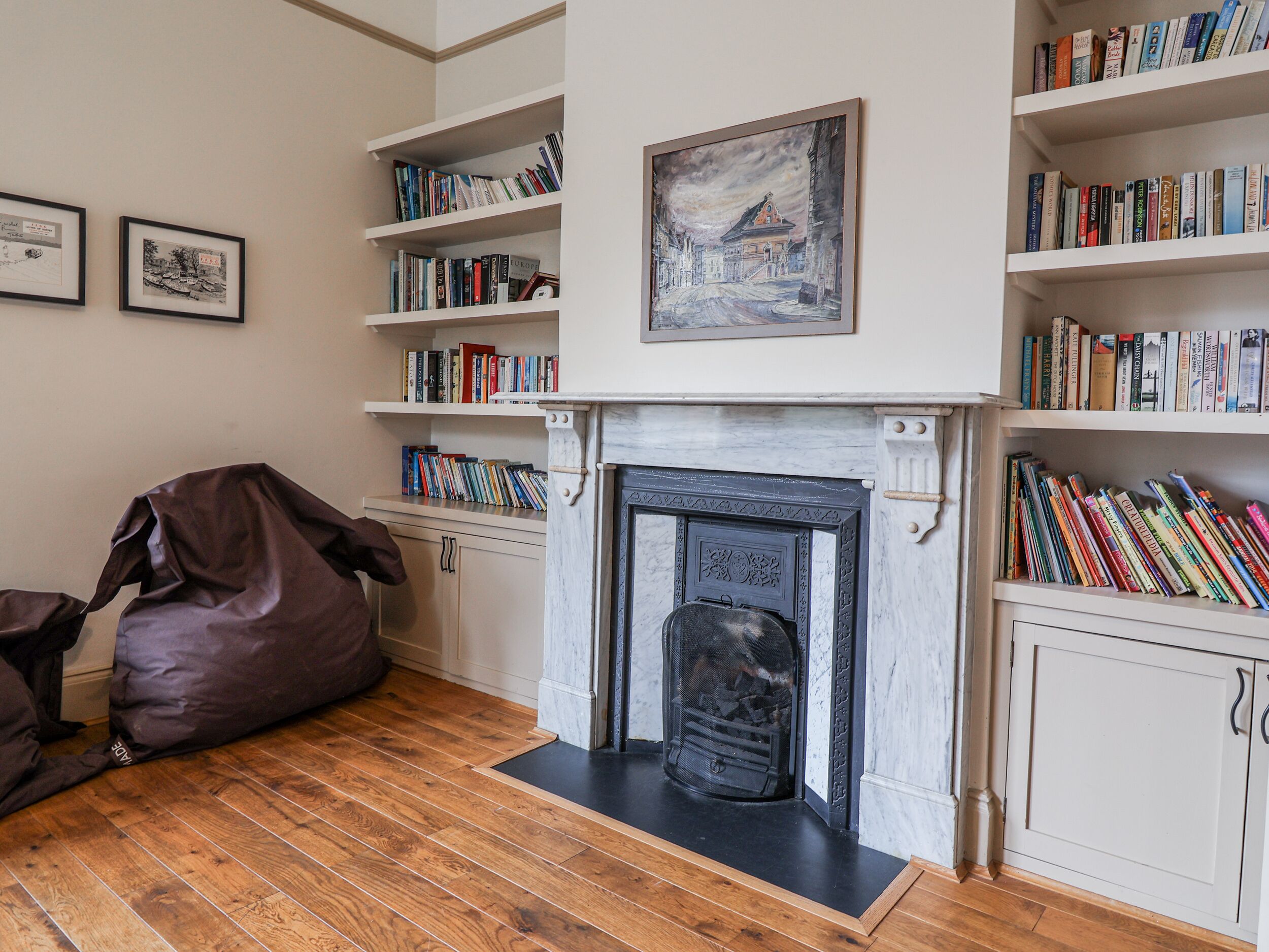 Un salon chaleureux avec une cheminée, un plancher en bois et des étagères remplies de livres.
