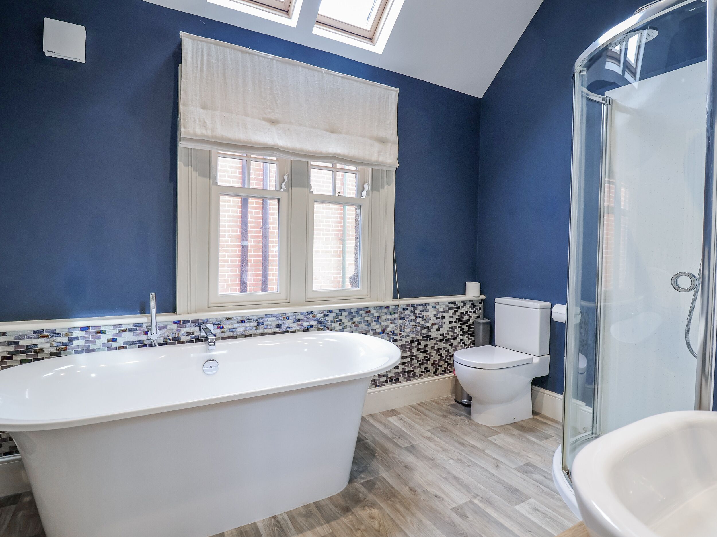 Een moderne badkamer met een vrijstaand bad, een toilet en een douchecabine met glazen wanden.