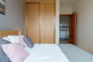 Un dormitorio con cama, almohadas y un armario de madera.