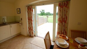 A kitchen with a dining area, a view of a garden, and a wooden chair.