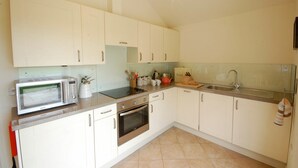 A kitchen with white cabinets, a microwave, a stove, and a sink.