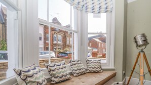 A room with a built-in bench by a large window overlooking a street. - Heron House, Southwold (Reydon)