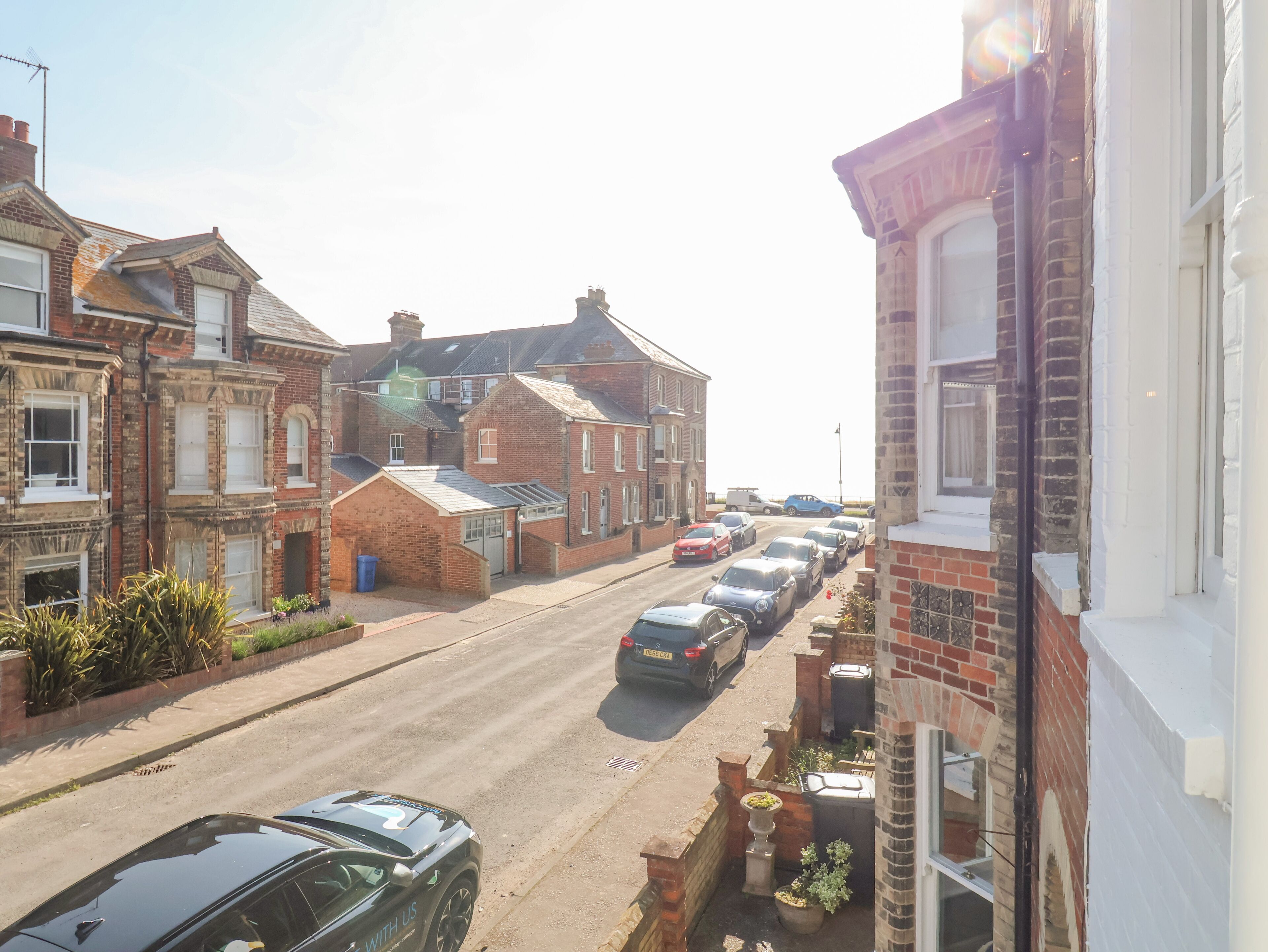 Une rue résidentielle bordée de maisons et de voitures garées.