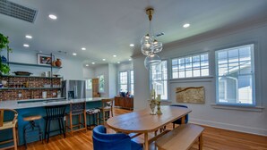 A modern kitchen with a brick backsplash, wooden countertops, and a dining area with a wooden table and blue chairs.