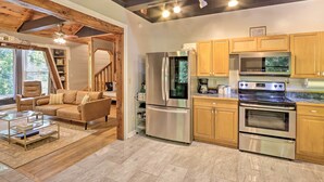 Una cocina moderna con electrodomésticos de acero inoxidable, armarios de madera y una mesa de centro de vidrio.