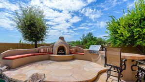 Une terrasse extérieure avec un foyer en pierre, des sièges et un barbecue.