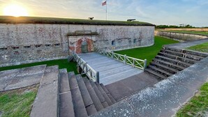 A historic fort with a flag, a wooden ramp, and a paved walkway. - Pet-friendly, 3 Blocks to Beach, Pool, #204 (Atlantic Beach)