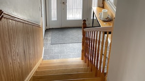 A staircase leading to a door with a stained glass window, a wooden railing, and a hanging light fixture.